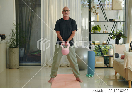 Mature man lifting weights at home to stay healthy 113638265
