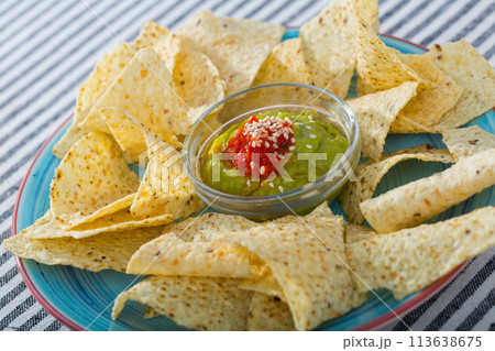 Corn chips nachos on plate with guacamole sauce at plate 113638675