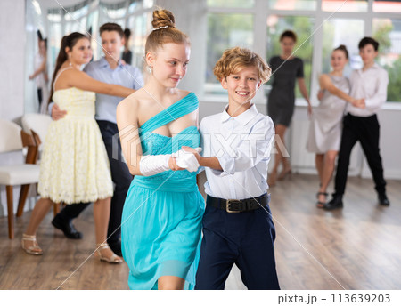 Positive teen boy and girl are dancing classic version of waltz in couple during lesson at studio Positive teen boy and girl are dancing classic version of waltz in couple during lesson at studio 113639203