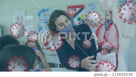 Multiple covid-19 cells floating against female teacher teaching anatomy at school 113639339