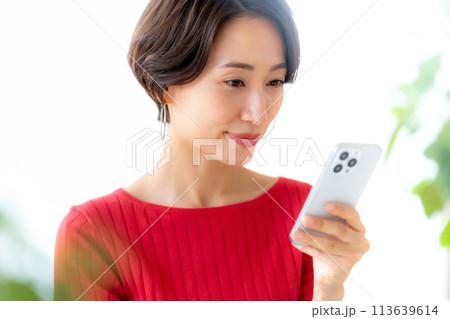 部屋でスマホを操作するミドル女性 113639614