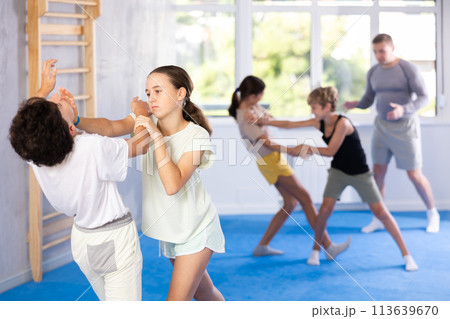 Boy and girl train to perform works out blow to jaw at opponent, while learning self-defense 113639670