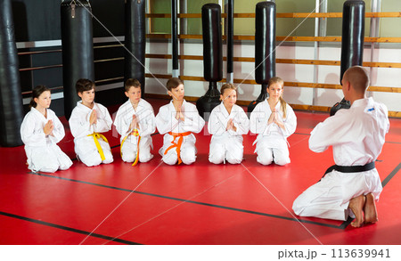 Coach in kimono tanding and greeting his students before lesson in gym 113639941