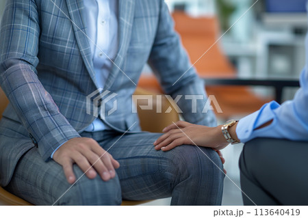 A woman touches the leg of a business man in a suit 113640419