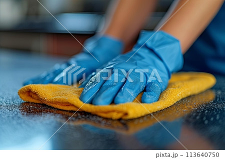Person is cleaning a table with a yellow cloth in blue gloves. Concept of cleanliness and orderliness 113640750