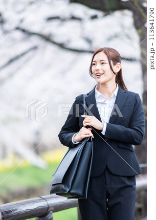 桜満開の春にスーツ姿で出勤する就職した若い女性 113641790