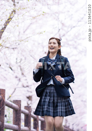 満開の桜の中、新学期を迎え急ぐ女子高生 満開の桜の中、新学期を迎え急ぐ女子高生 113641810