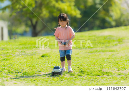 芝生の公園でラジコンで遊ぶ子ども 113642707