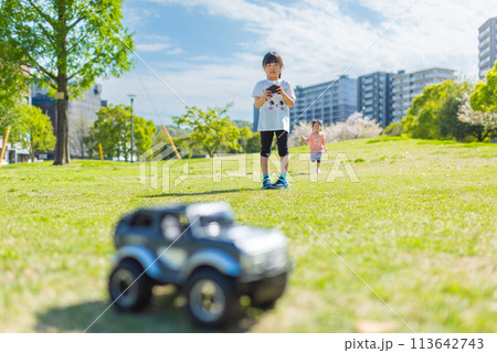 芝生の公園でラジコンで遊ぶ子ども 113642743