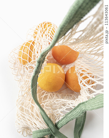 Fresh unpeeled oranges placed in reusable white mesh bag Fresh unpeeled oranges placed in reusable white mesh bag 113643061