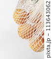Fresh unpeeled oranges placed in reusable white mesh bag 113643062