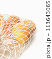 Fresh unpeeled oranges placed in reusable white mesh bag 113643065