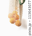 Fresh unpeeled oranges placed in reusable white mesh bag 113643077