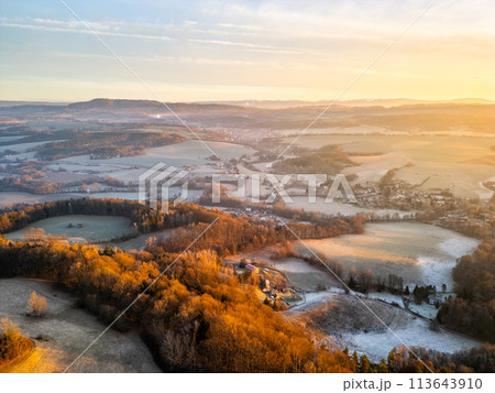 Golden sunrise bathing the rolling landscape of Bohemian Paradise with villages and fields in serene dawn light. Aerial drone photography. 113643910