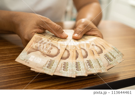 Asian business woman holding Thai banknote currency money. 113644461