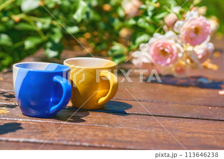 Tea time. Coffee break. Blue yellow cups on wooden in blooming garden 113646238