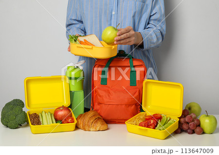 Lunch boxes with food and a school backpack Lunch boxes with food and a school backpack 113647009