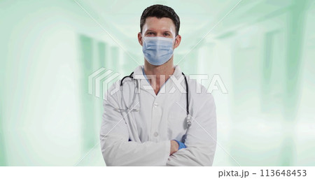 Portrait of caucasian male doctor wearing face mask against white background 113648453