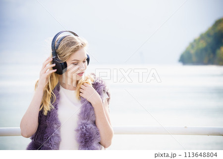 Happy woman wearing headphones outdoor 113648804