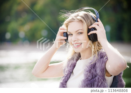 Happy woman wearing headphones outdoor 113648808