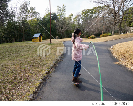 冬の公園でキャスターボードを遊んでいる小学生の女の子の様子 冬の公園でキャスターボードを遊んでいる小学生の女の子の様子 113652050