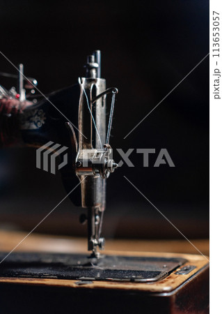 Old sewing machine stands on the table at home ready to work and sew. Old sewing machine stands on the table at home ready to work and sew. 113653057