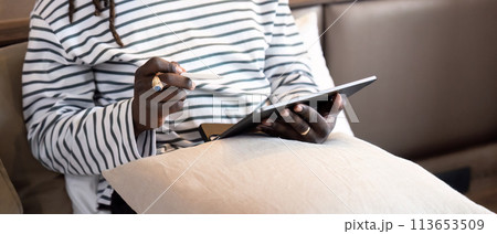 Smiling young African American man using digital tablet remote job sitting on the bed at home. concept online technology communication 113653509