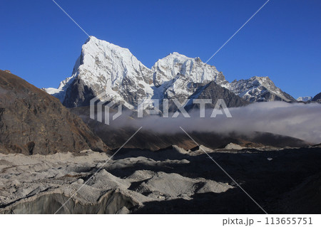 Lower part of the Ngozumba Glacier and snow covered mountains Cholatse and Tobuche, Nepal. 113655751