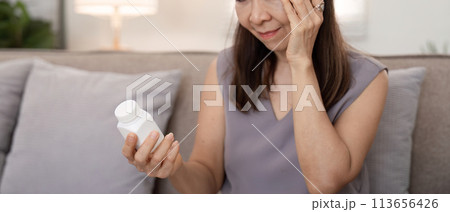 Senior lady suffering from pain or headache doubt about taking painkiller pill, upset aged woman have antibiotics or prescribed medicines 113656426