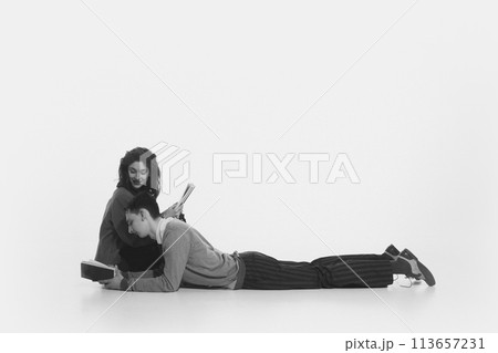 Young couple, man and woman spending time together and reading books isolated on white background. Black and white 113657231