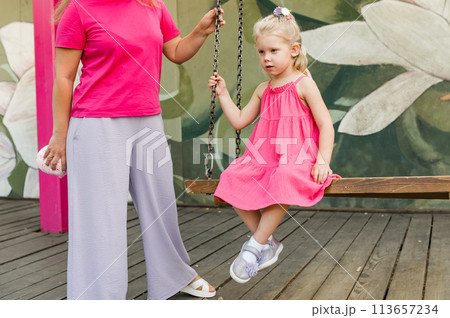 Deaf child with cochlear implant for hearing audio and aid for impairment having fun and laughs with mother outdoor in summer. Sound fitting device to help with communication listening and interaction 113657234