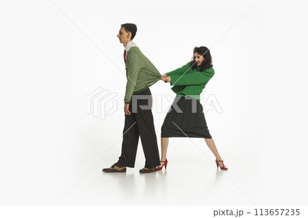 Emotionless young man walking away while woman pulling his with sweater. Emotional lifestyle situation of married couple 113657235