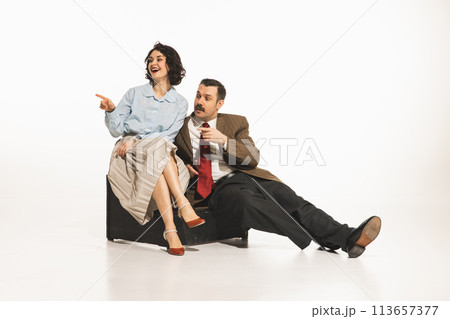 Elegant young woman and man in classical retro clothes sitting, looking away, pointing and taking, white background. Discussing, rumors, gossips Elegant young woman and man in classical retro clothes sitting, looking away, pointing and taking, white background. Discussing, rumors, gossips 113657377