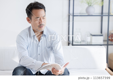 老眼で本が読みにくくなっている男性 113657399