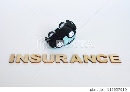 Insurance text with upside down toy car background. Car insurance concept Insurance text with upside down toy car background. Car insurance concept 113657910