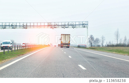a truck passes through a toll frame against the backdrop of the sun and car traffic. Concept map of toll roads in the country, copy space for text, business a truck passes through a toll frame against the backdrop of the sun and car traffic. Concept map of toll roads in the country, copy space for text, business 113658238