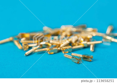 Lots of metal dental pins on a blue background. The concept of installing a tooth and a dental crown on pins in orthodontics, macro 113658251