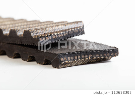 Torn timing belt on a white background, close-up. Timing belt break concept, industry Torn timing belt on a white background, close-up. Timing belt break concept, industry 113658395