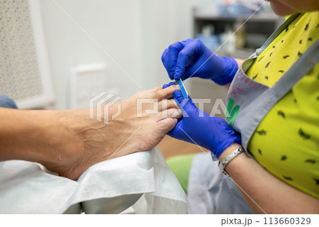 concept of male pedicure, cosmetologist makes classic pedicure for an elderly male client. concept of male pedicure, cosmetologist makes classic pedicure for an elderly male client. 113660329