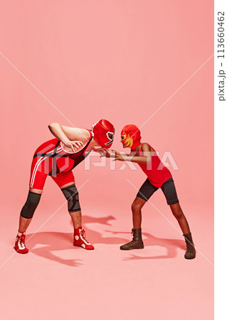 Middle-aged man with little boy stands in attack pose and looking to each other with angry emotions against pink studio background. Middle-aged man with little boy stands in attack pose and looking to each other with angry emotions against pink studio background. 113660462