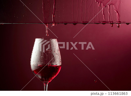 Red wine flows down into a glass. Red wine flows down into a glass. 113661863