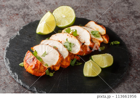 Sliced barbecue chipotle chicken breast served with lime and cilantro close-up on a slate plate. Horizontal 113661956