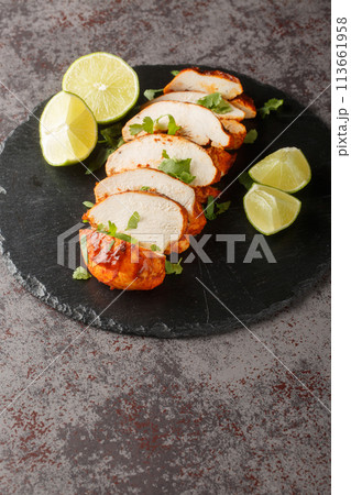 Delicious spicy chipotle chicken breast served with lime and cilantro close-up on a slate plate. Vertical 113661958