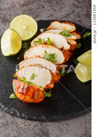 Fried chipotle chicken breast served with lime and cilantro close-up on a slate plate. Vertical 113661959