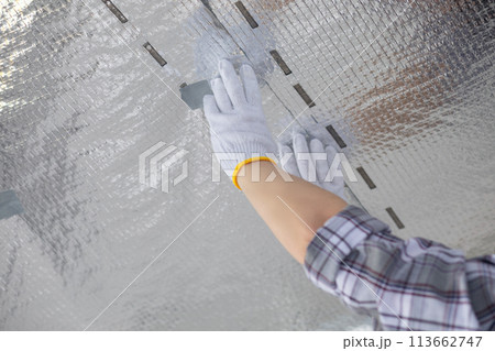 Worker tapping vapor barrier joints on ceiling. Worker tapping vapor barrier joints on ceiling. 113662747
