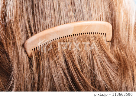 Straight brown hair with wooden comb closeup 113663590