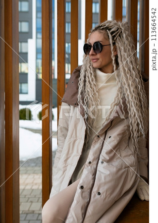 Woman With Long Blonde Hair Sitting on a Bench 113664542