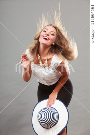 Woman wearing long black white dress holding sun hat 113664561