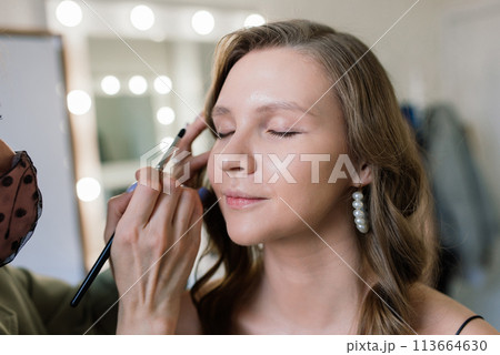 Woman make-up artist work in her studio with model Woman make-up artist work in her studio with model 113664630
