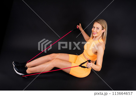 Sportswoman performs exercises for the muscles of the chest. Workout with resistance band. 113664657